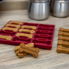Dog treats with 'Good Girl' text next to a red silicone mold on a wooden surface.