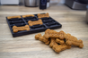 Dog treats with 'WOOF' and 'HOMEMADE' text on a wooden surface next to a mold.